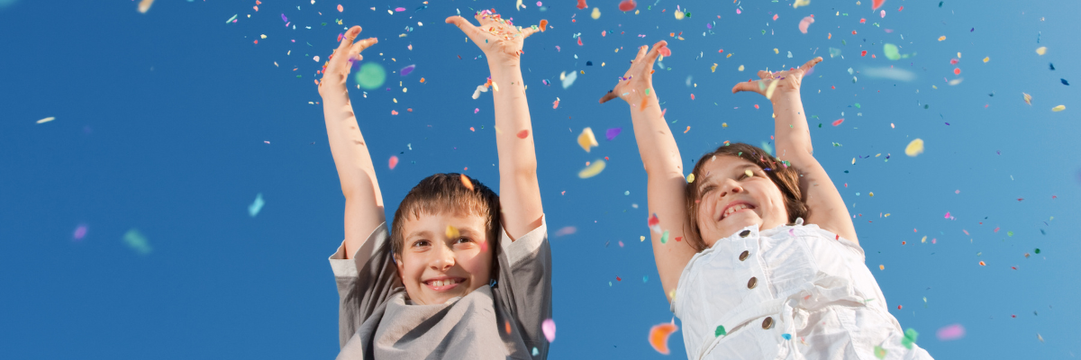 Two children celebrating with streamers against a blue sky