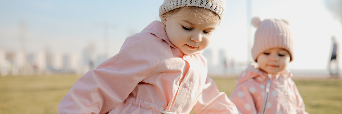 Two little girls hold hands in the park